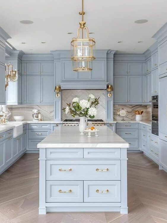 light blue kitchen cabinets with marble counters and bass accents hardware